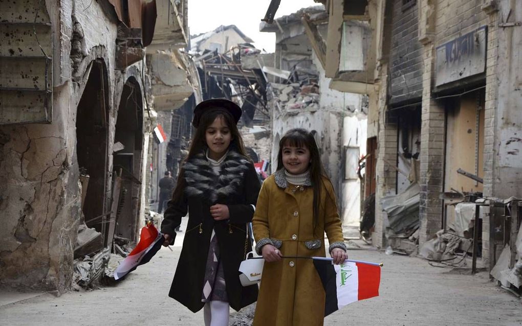 Twee Iraakse meisjes lopen met de Iraakse vlag in de hand door de straten van Mosul, bij de opening van een markt vorige week.  beeld AFP, Ahmad Muwafaq