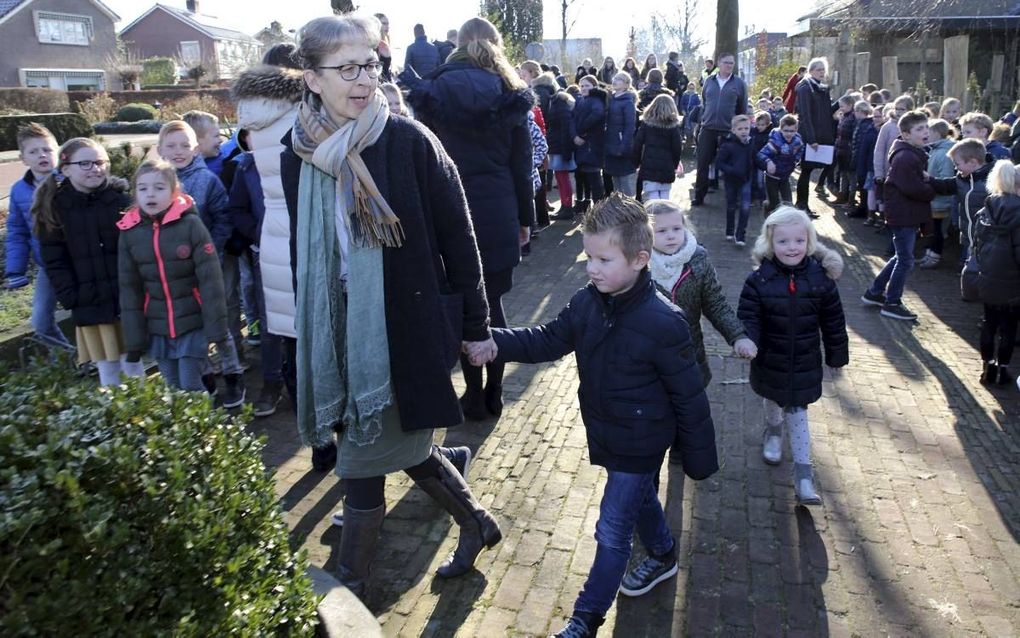 Kinderen van de Koning Willem-Alexanderschool in Staphorst zijn naar buiten ‘gevlucht’ vanwege een ontruiming. Tegen de boom geleund, staat cursusleider Bertus van Wincoop. beeld Eelco Kuiken
