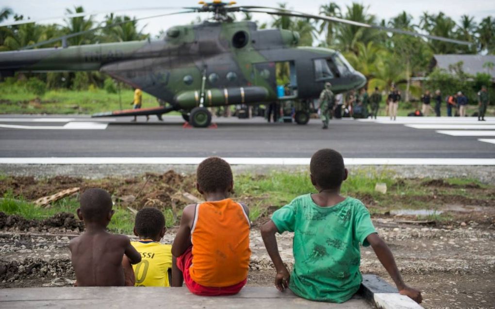 Drie Papoea-jongens kijken toe hoe een Indonesische legerhelikopter landt in Asmat. Daar brak eind vorige maand een dodelijke mazelen-epidemie uit.  beeld AFP,  Bay Ismoyo