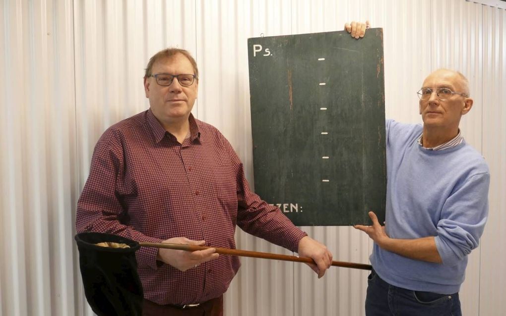 Jan Noorlandt (l.) en Machiel Vennik tonen het oude psalmbord van de christelijke gereformeerde kerk Teuge. beeld RD