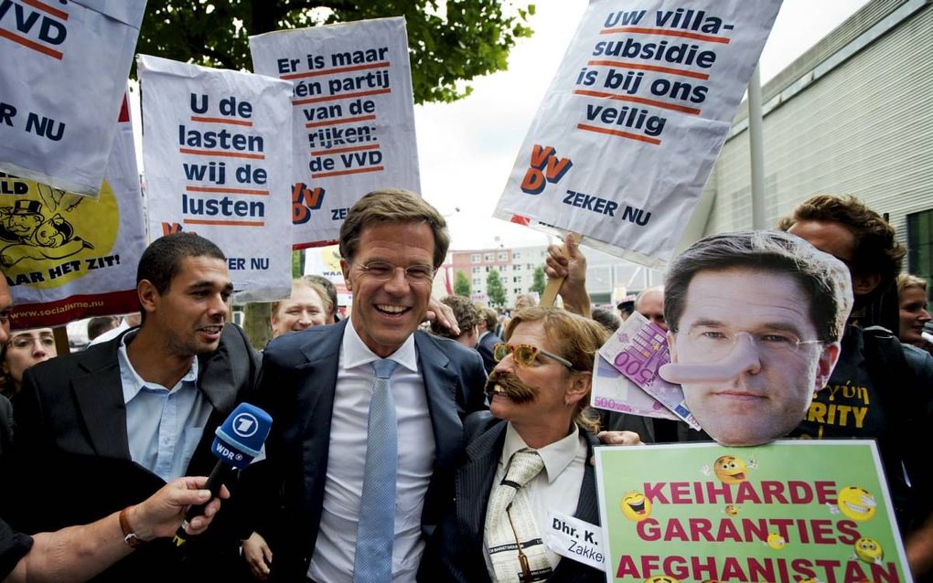 VVD-leider Rutte passeert enkele demonstranten, voorafgaand aan een verkiezingscongres van zijn partij in Rotterdam.  beeld ANP, Robin Utrecht