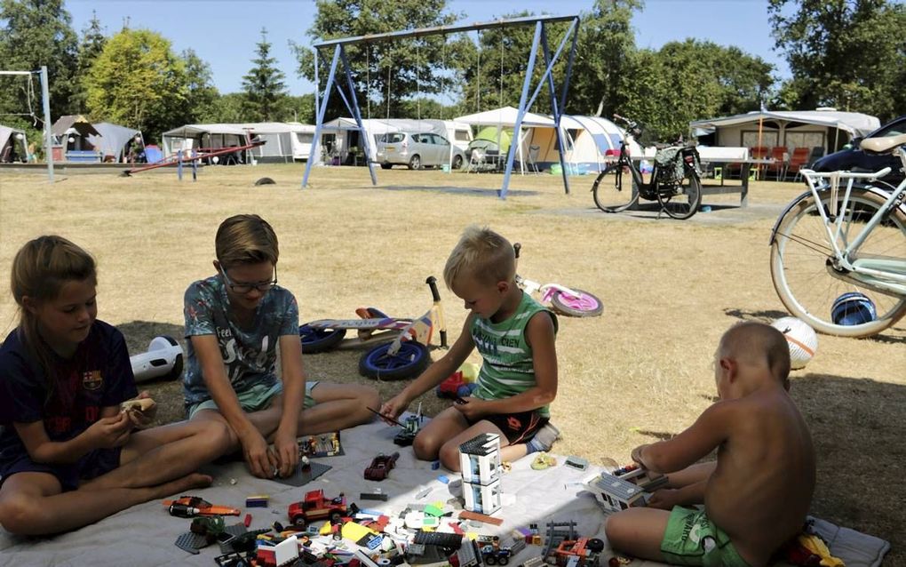 In de schaduw van de tent op vakantiepark De Kleine Belties in Hardenberg. Het gras op de camping is kurkdroog en vergeeld. „Er valt niet tegenop te sproeien.” beeld Frank Uijlenbroek