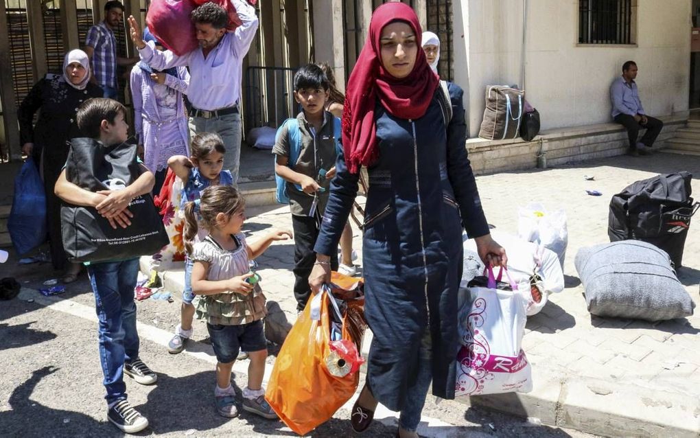 Syrische vluchtelingen passeren met hun bezittingen de Libanees-Syrische grensovergang bij Masnaa om op een bus te stappen die hen naar Syrïe terugbrengt. beeld AFP, Hassan Jarrah