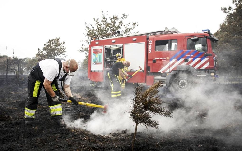 Brandweerlieden blussen woensdag na op de hei bij het Drentse Wateren. Door de brand is zo’n 75 hectare heide zwartgeblakerd.  beeld ANP, Remko de Waal