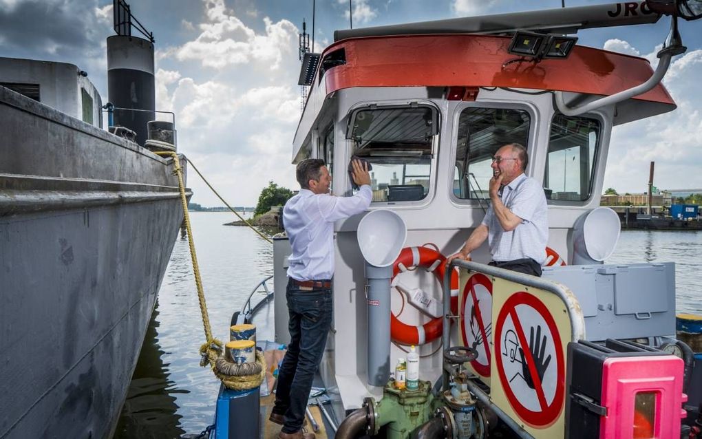 Martin Brijder poetst onder het toeziend oog van Wim Nobel de ruit van de stuurhut van diens bunkerbootje. beeld Cees van der Wal