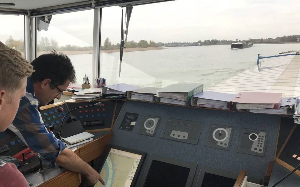 Schipper Cornelis Bernouw van binnenvaartschip Prinsenland wijst zijn matroos op het navigatiesysteem waar de rivier diep is.  beeld RD