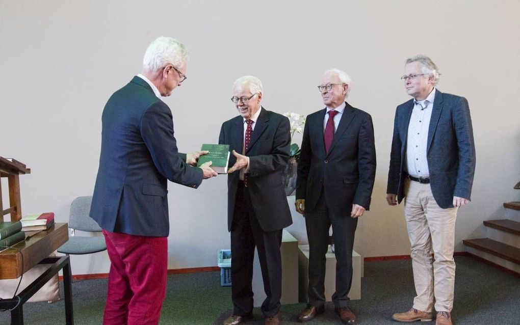 Nico de Waal (KokBoekencentrum) overhandigt het eerste deel van Van Rulers werk over de kerk aan de redactie (van links naar rechts) dr. P. van den Heuvel, drs. J. Stelwagen en dr. D. van Keulen. beeld RD, Anton Dommerholt