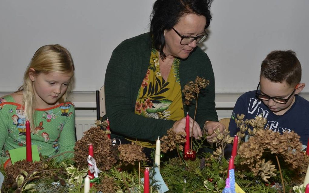 Groepsleerkracht Wilma van der Maas van basisschool De Rank werkt met leerlingen aan kerststukjes voor ouderen. beeld André Bijl