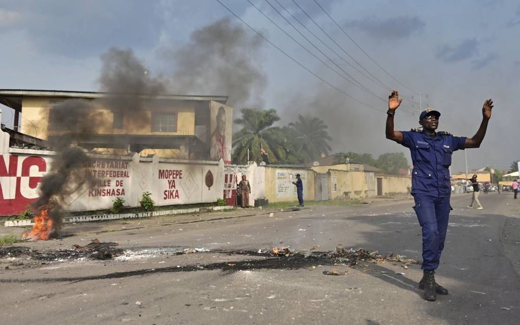 Een Congolese agent probeert tijdens protesten in Kinshasa boze aanhangers van Martin Fayulu te kalmeren, maandag. beeld AFP, Tony Karumba