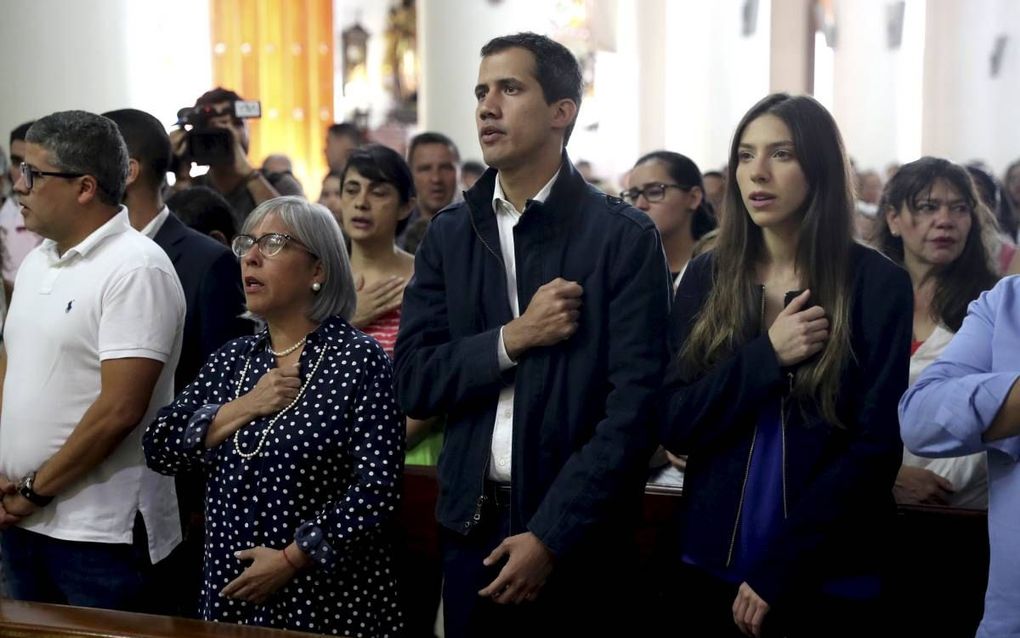 Juan Guaido (m.) bezocht met zijn moeder (l.) en vrouw (r.) de zondag na zijn eedaflegging onder grote belangstelling een mis. beeld EPA, Miguel Gutiérrez