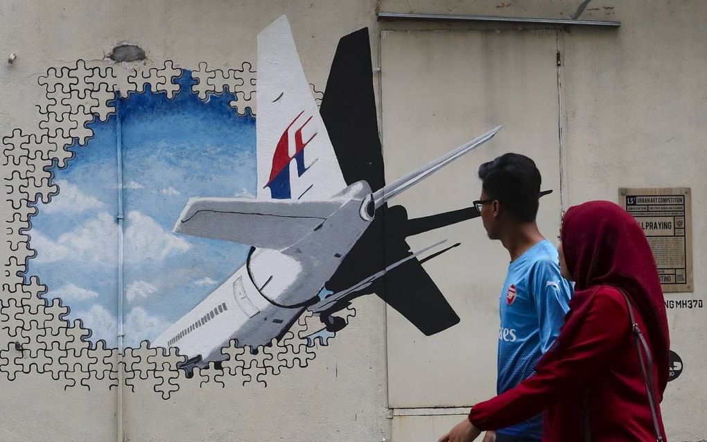 Voorbijgangers passeren in Kuala Lumpur een muurschildering van de vermiste Boeing 777 van Malaysia Airlines. Vlucht MH370 is vandaag vijf jaar van de radar verdwenen.  beeld EPA, Fazry Ismail