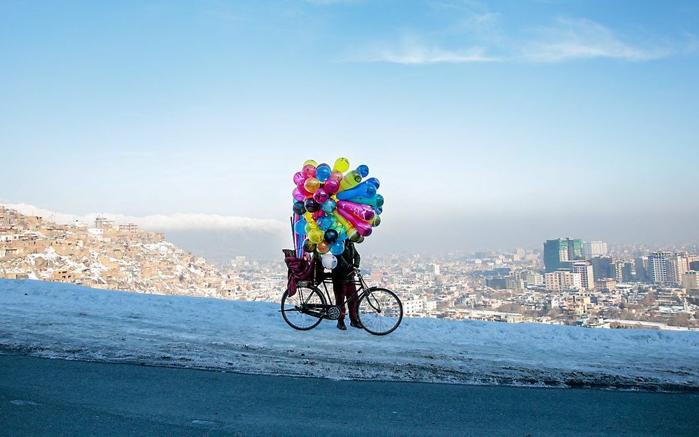 Een Afghaanse straathandelaar met zijn ballonnen op een heuvel in Kabul. beeld EPA