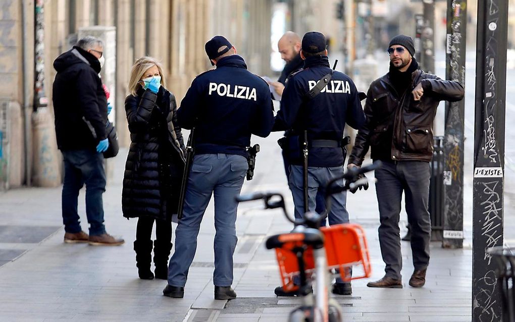 Italiaanse politieagenten controleren in Milaan of burgers een geldige reden hebben om de straat op te gaan. Politie en soldaten worden in het hele land ingezet om ervoor te zorgen dat burgers thuisblijven in een poging verdere verspreiding van het corona