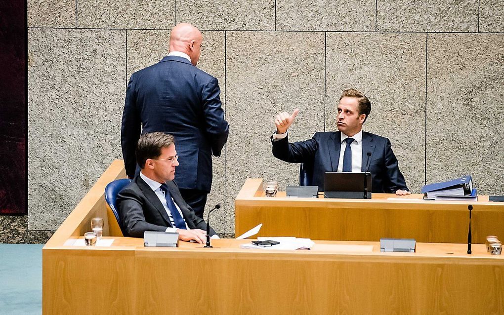 Minister De Jonge (r.) steekt een dikke duim op naar minister Grapperhaus (m.) als die na een korte ondervraging door de Kamer de vergaderzaal weer verlaat. beeld ANP, Bart Maat