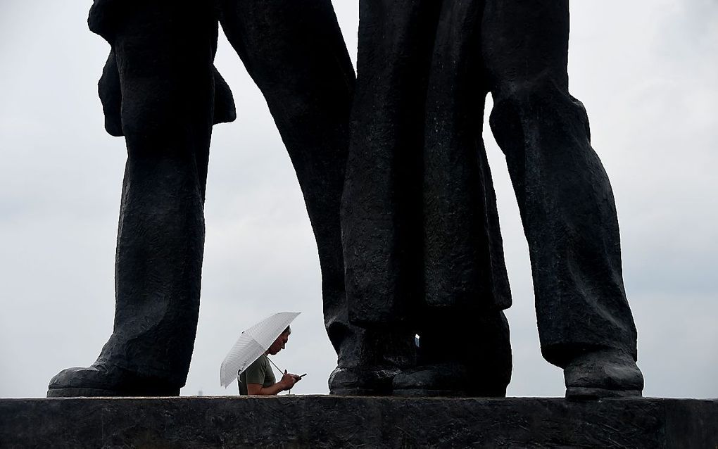 De regen daalt neer in de Oekraïense hoofdstad Kiev bij het Sovjetmonument. beeld AFP