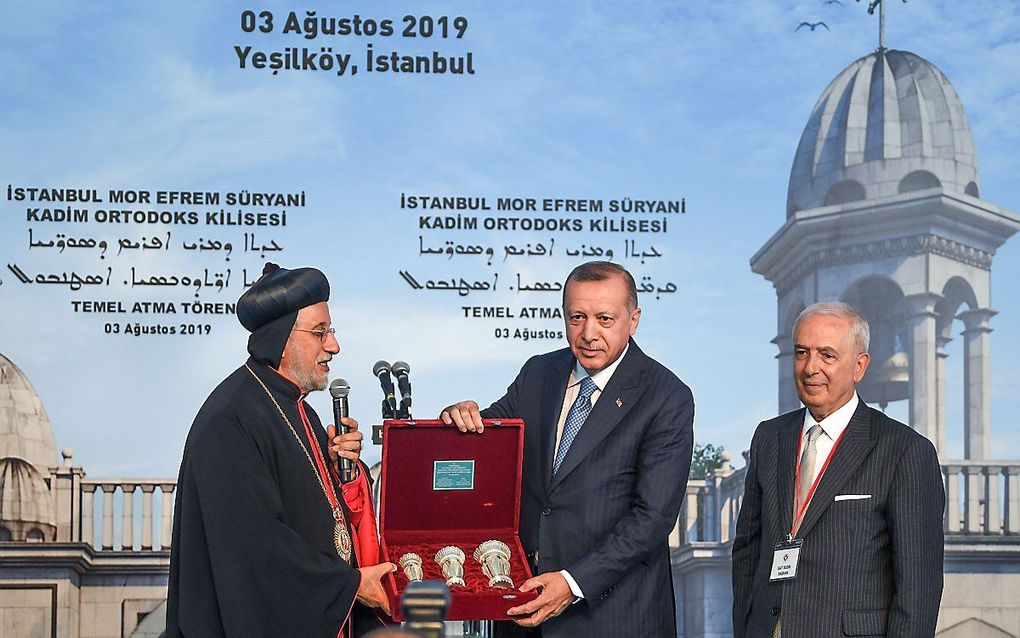 De Syrisch-orthodoxe patriarch Yusuf Cetin (l.) overhandigt een geschenk aan president Erdogan (m.) ter gelegenheid van de eerstesteenlegging van een christelijke kerk in Istanbul. beeld AFP, Ozan Kose