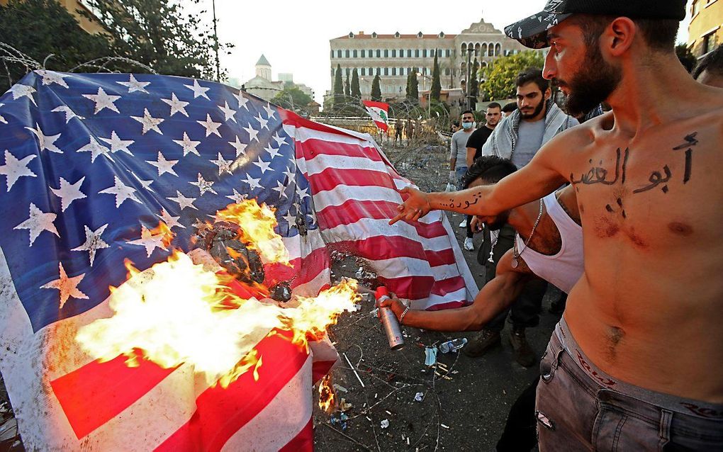 Libanese demonstranten steken een Amerikaanse vlag in brand in Beiroet. beeld AFP