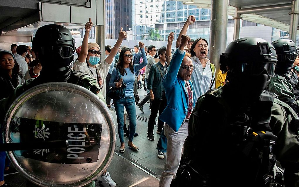 De oproerpolitie versperde betogend kantoorpersoneel vrijdag de doorgang bij een protest in Hongkong. beeld AFP