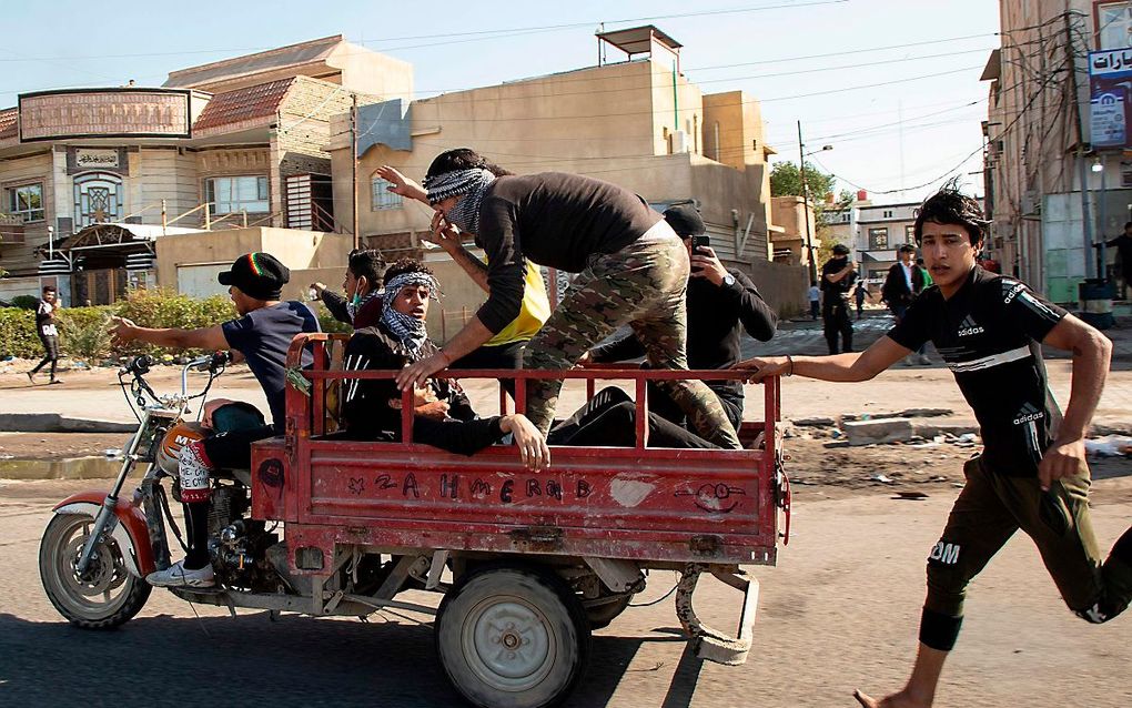 Een gewonde demonstrant wordt afgevoerd in Bagdad. beeld AFP