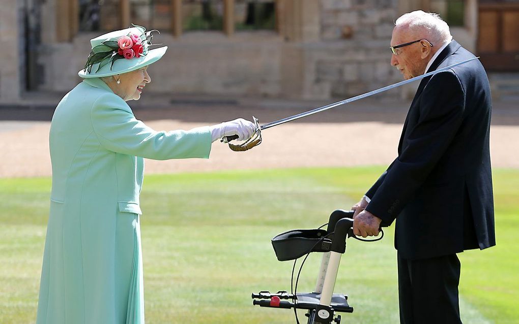 De Britse koningin Elizabeth slaat Tom Moore tot ridder. beeld AFP