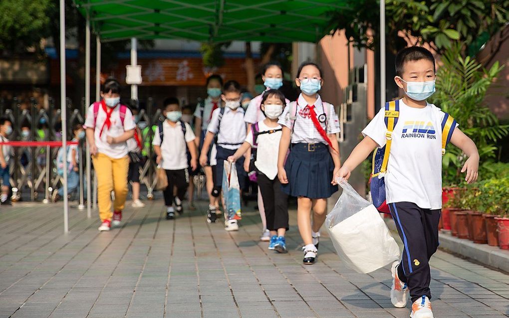 Jonge Chinezen gingen dinsdag met mondkapjes op naar school.  Als aerosolen inderdaad een rol spelen bij besmetting, dan worden de kapjes in afgesloten ruimtes als klaslokalen extra belangrijk.  beeld AFP, STR