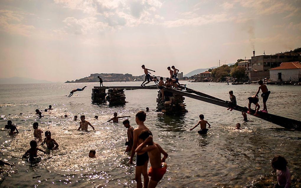 Migranten en vluchtelingen zoeken op Lesbos verkoeling in zee. beeld ANGELOS TZORTZINIS / AFP