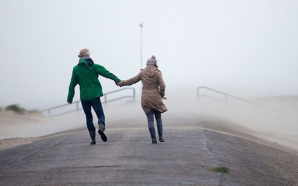 Mensen op de Oosterscheldekering tijdens een herfststorm in 2016. beeld ANP