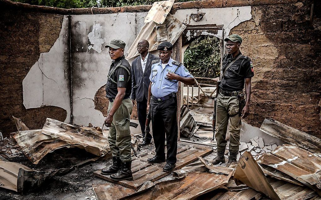 Politieofficieren inspecteren een verwoest huis, in de brand gestoken door Fulani-herders bij een eerdere aanval vorig jaar. beeld AFP, Luis Tato