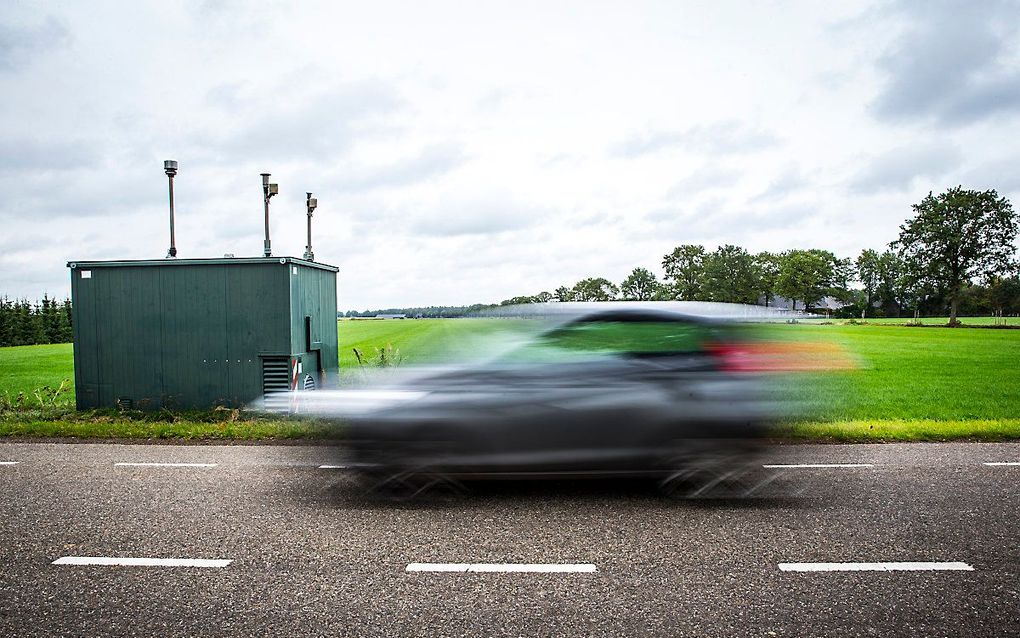 Een auto rijdt langs een meetstation van de RIVM. beeld ANP