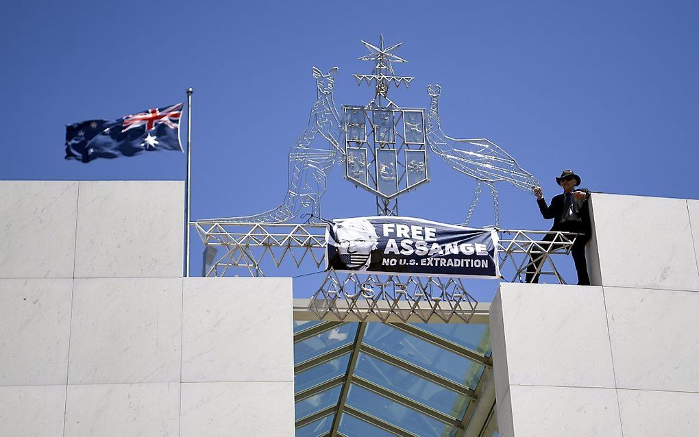 „Julian Assange zit gevangen omdat hij de waarheid openbaarde over onder meer Irak en Jemen. Ook Nederland wilde hem geen politiek asiel verlenen.” Foto: een demonstrant vraagt boven op het parlementsgebouw in het Australische Canberra om de vrijlating va