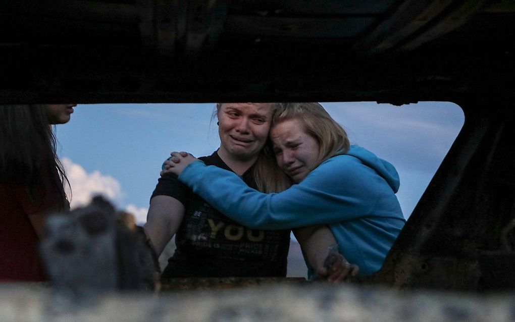 Familieleden rouwen bij de uitgebrande auto. beeld AFP