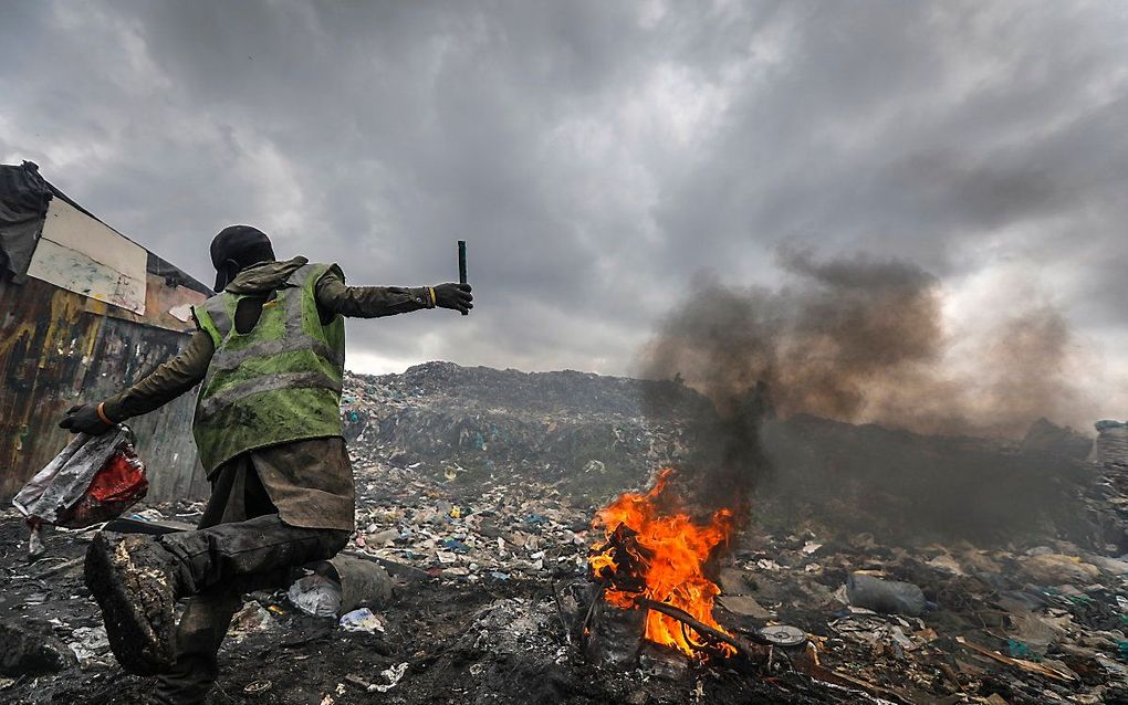 Op een vuilnisbelt vol elektronisch afval in Nairobi, Kenia steekt een man een afgedankte auto in brand. Hij wil er koper uithalen. beeld EPA, Dai Kurokawa