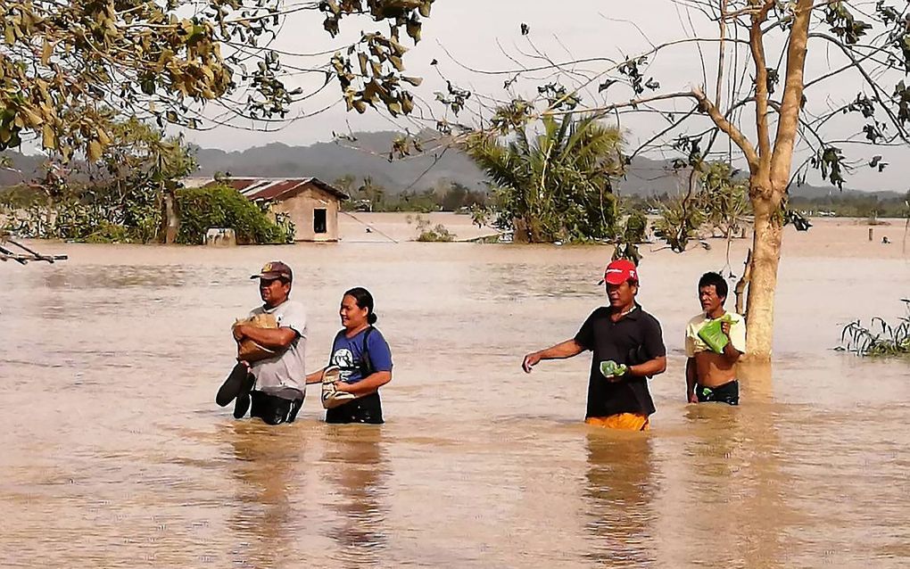 Inwoners van Ormoc waden door het water na overstromingen als gevolg van de tyfoon Phanfone. beeld AFP