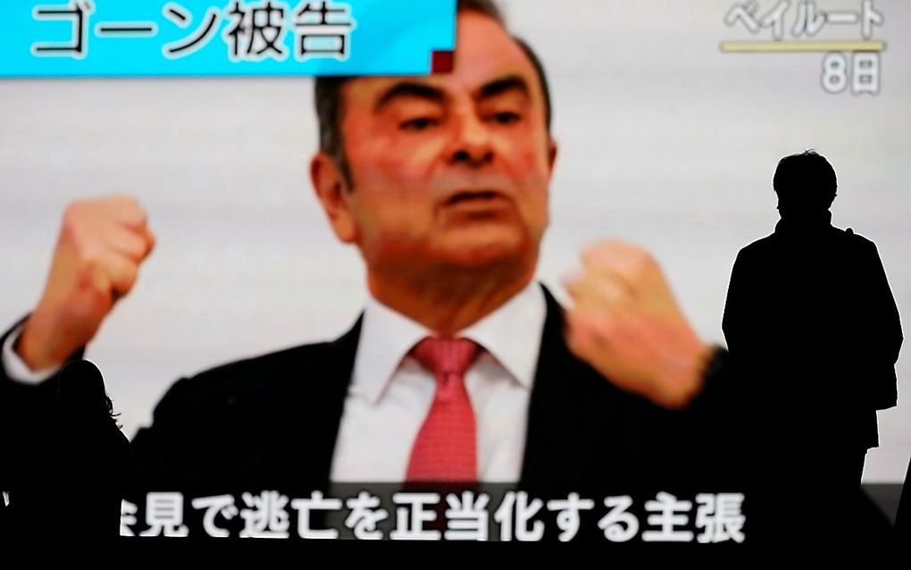 Iemand in Tokyo loopt voorbij een groot scherm waarop Carlos Ghosn zichtbaar is. beeld EPA