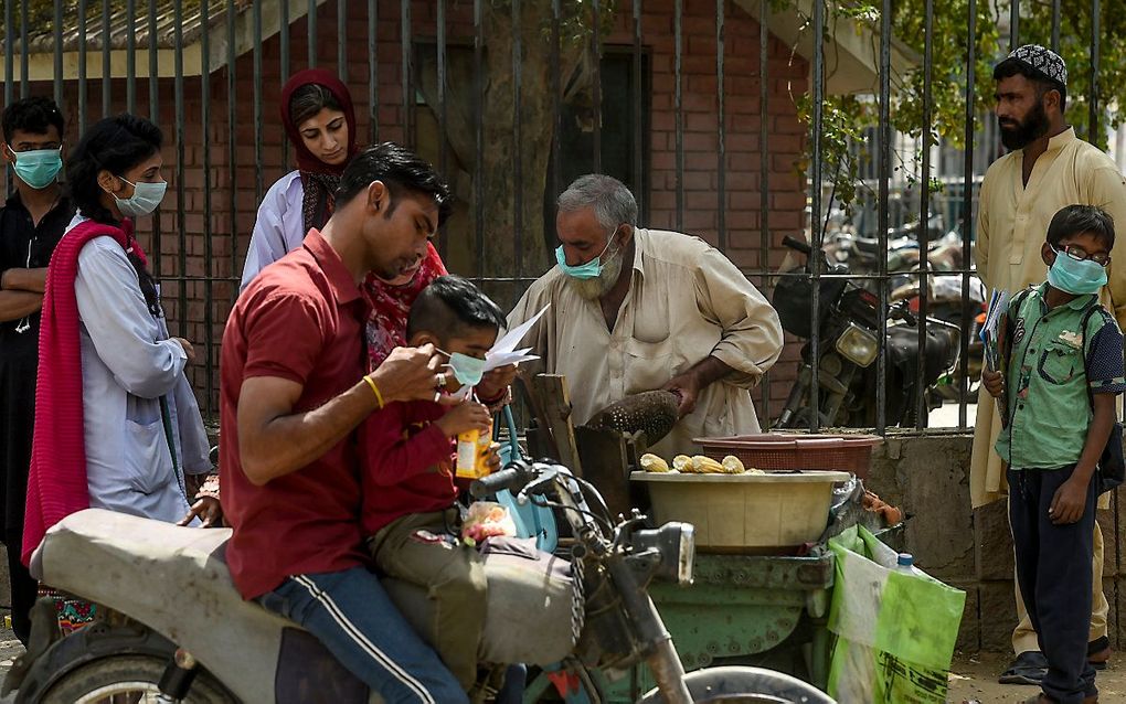 Klanten bij een straatverkoper in Karachi, Pakistan. beeld AFP