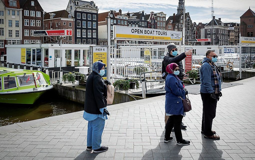 In een uitgestorven Amsterdam lopen toeristen met mondkapjes. beeld ANP, Robin van Lonkhuijsen