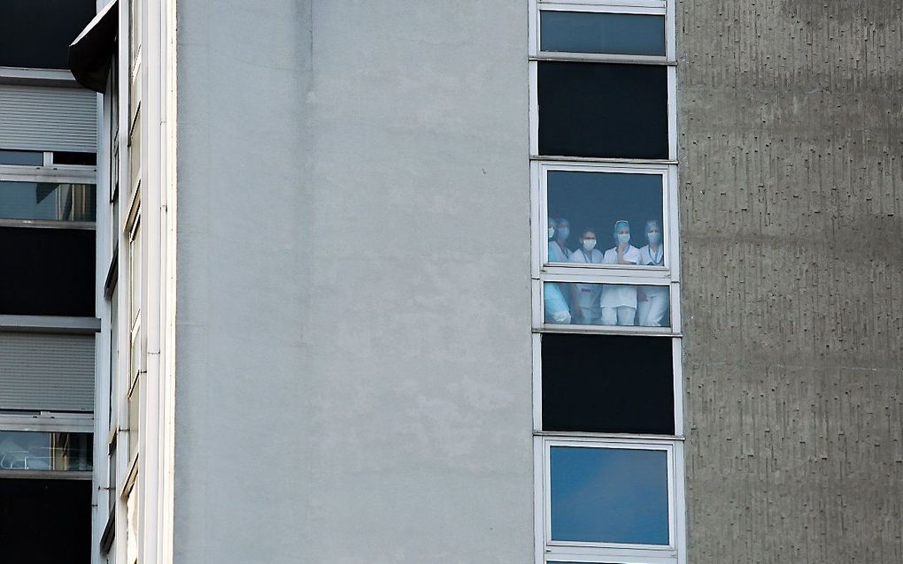 Ziekenhuispersoneel in Mulhouse kijkt naar het bezoek van president Macron aan Mulhouse, vorige week. beeld AFP