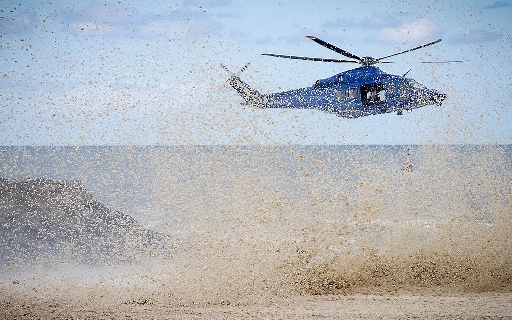 Een politiehelikopter blaast schuim tussen rotsblokken vandaan, zodat reddingswerkers daar kunnen zoeken naar het lichaam van de vijfde surfer. beeld ANP