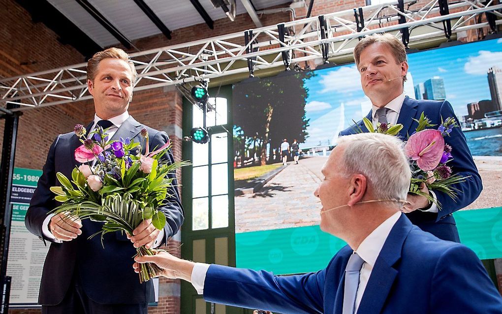 CDA-partijvoorzitter Rutger Ploum (m.) reikt bloemen uit aan de nieuwe partijleider Hugo de Jonge (l.) Rechts diens tegenkandidaat, Kamerlid Pieter Omtzigt. beeld ANP, Sem van der Wal