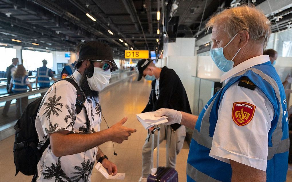 Medewerkers van de GGD ondervragen reizigers op luchthaven Schiphol. beeld ANP, Evert Elzinga