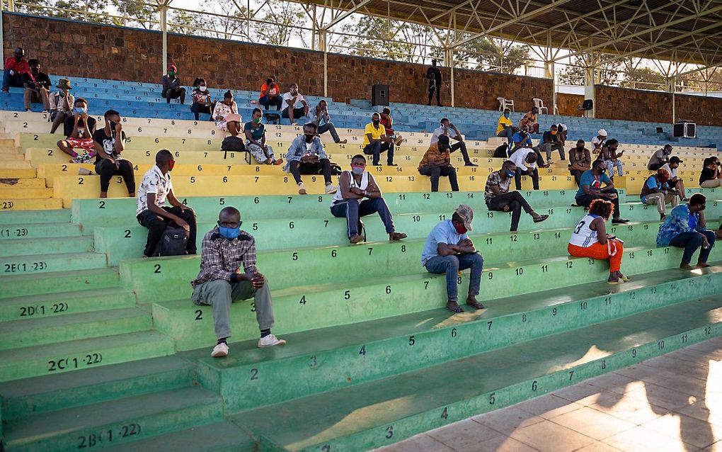 Mensen die coronamaatregelen negeerden, moeten verplicht naar de preventietoespraken luisteren in een stadion in Kigali, Rwanda. beeld AFP