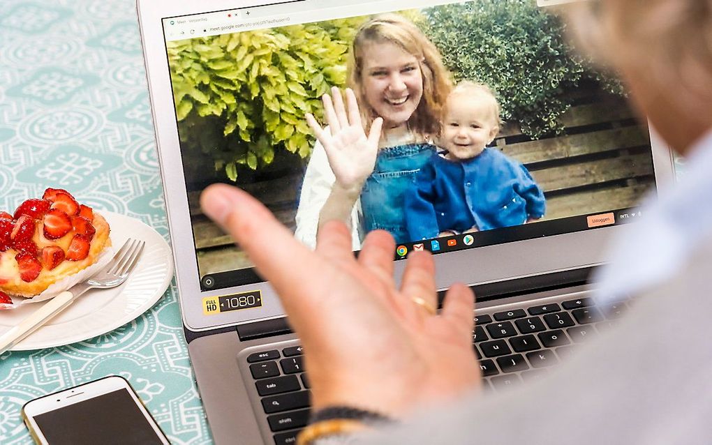 Een man en een vrouw met kind begroeten elkaar tijdens een online videogesprek. beeld ANP LEX VAN LIESHOUT