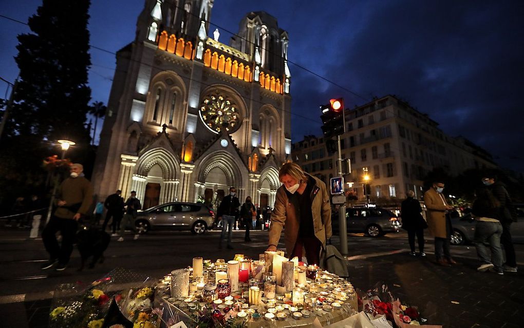 Mensen steken een kaars aan buiten de basiliek Notre-Dame de l'Assomption in Nice op 30 oktober 2020, een dag nadat een mesaanvaller drie mensen doodde en de keel van twee mensen doorsneed, in de kerk van de stad aan de Franse Rivièra, en de politie arres