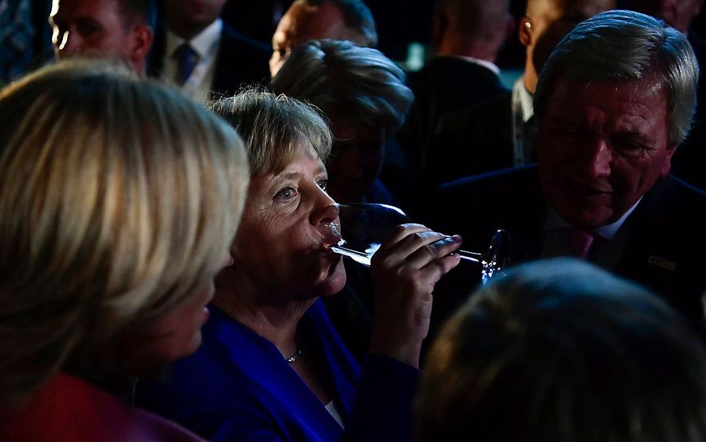 Merkel drinkt een glas wijn na het debat. beeld AFP