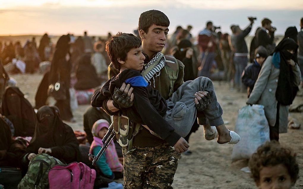 Een gewond kind wordt uit het Syrische IS-bolwerk Baghouz gedragen. beeld AFP