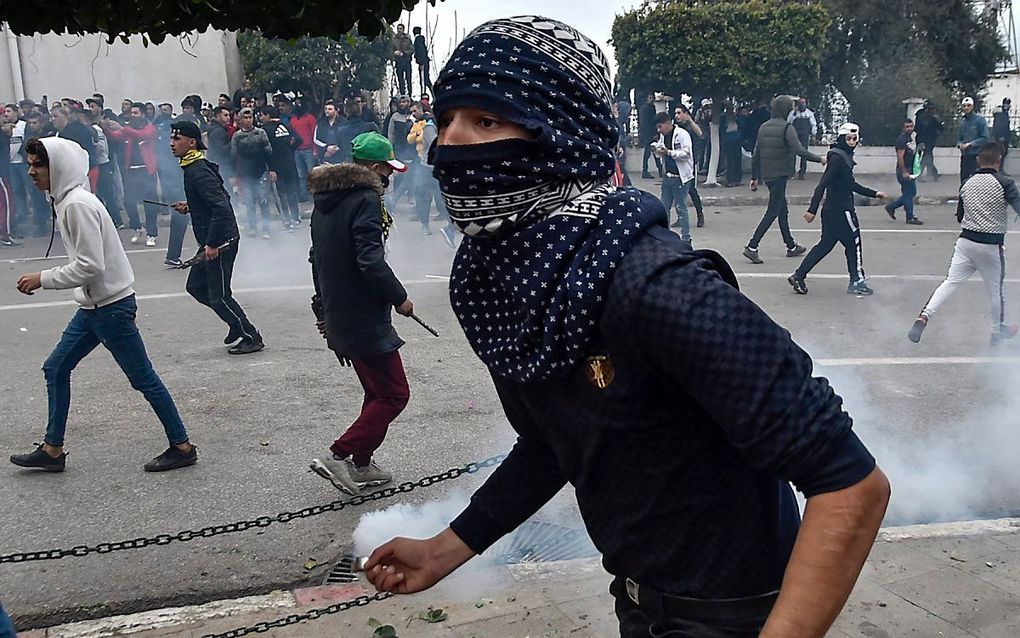 Een Algerijnse demonstrant met een traangasgranaat. beeld AFP