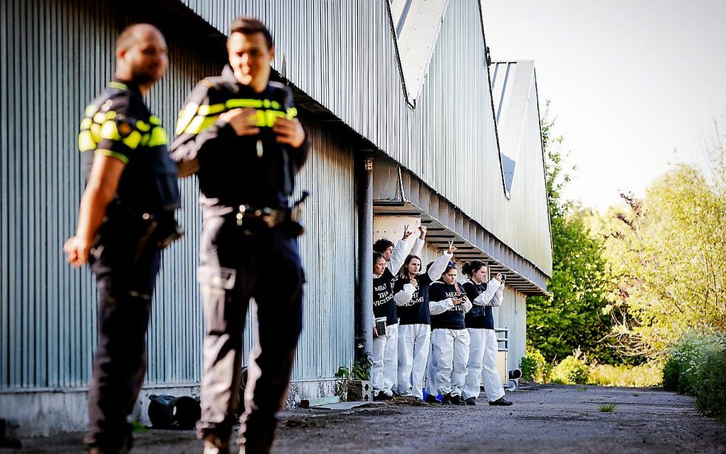 Politie en op de achtergrond actievoerders bij de boerderij. beeld ANP