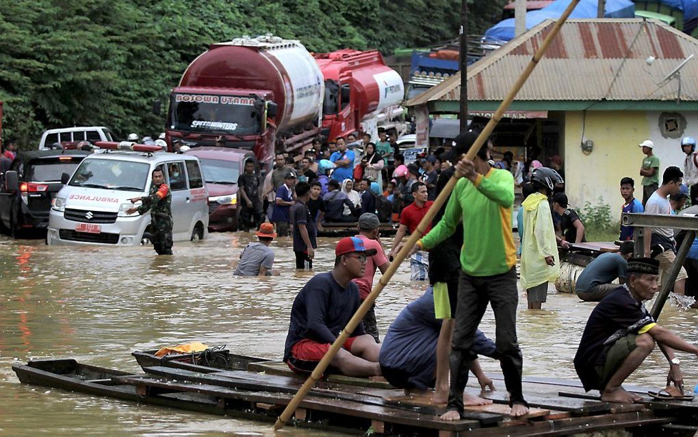 Gestrand verkeer bij een weg die onder water staat in Andadowi, in de Indonesische provincie Zuidoost-Sulawesi. Door grote overstromingen moesten alleen in deze provincie al ruim 4.000 mensen evacuëren. beeld AFP, Suwarjono