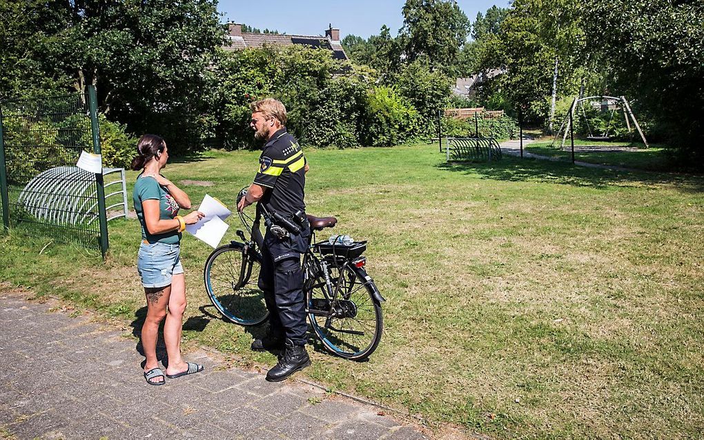 Een buurtbewoner spreekt met een wijkagent bij het speeltuintje in Assen. beeld ANP