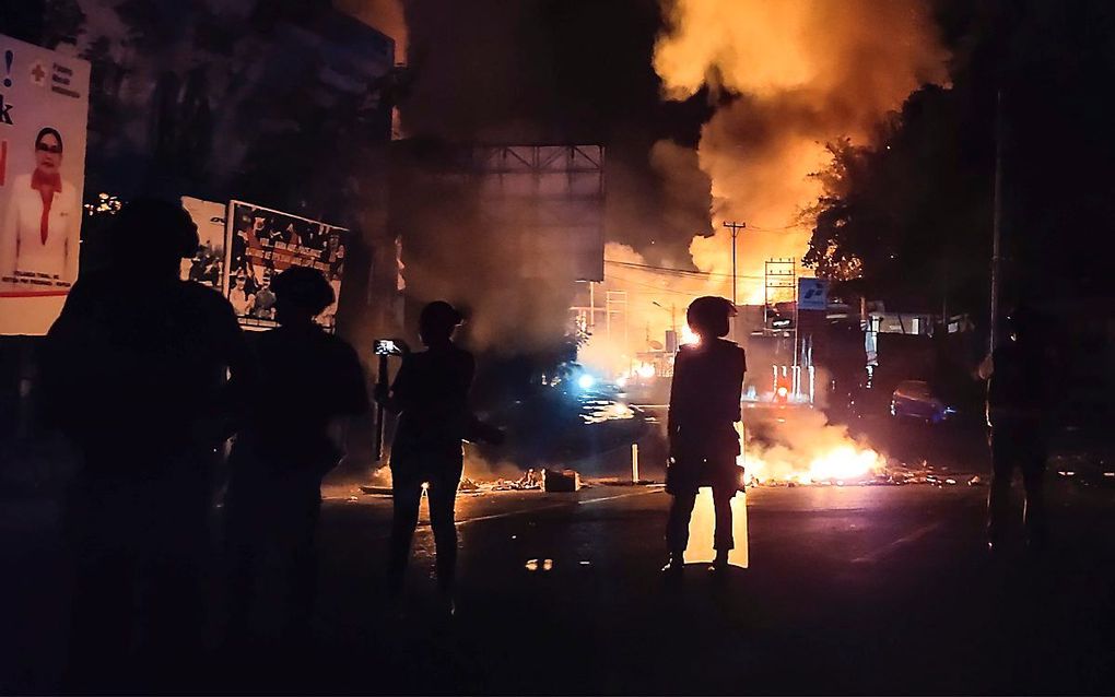 Veiligheidstroepen kijken naar een brandend overheidsgebouw in Jayapura, de hoofdstad van Papoea. Het is al geruime tijd onrustig in de Indonesische provincie. beeld AFP